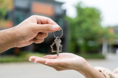 Woman buying or rent new home she holding key front of new house